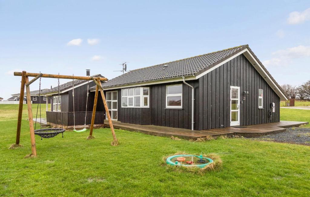una casa nera con un'altalena e un parco giochi di Holiday Home Vinkelbæk Nordborg Denm a Nordborg