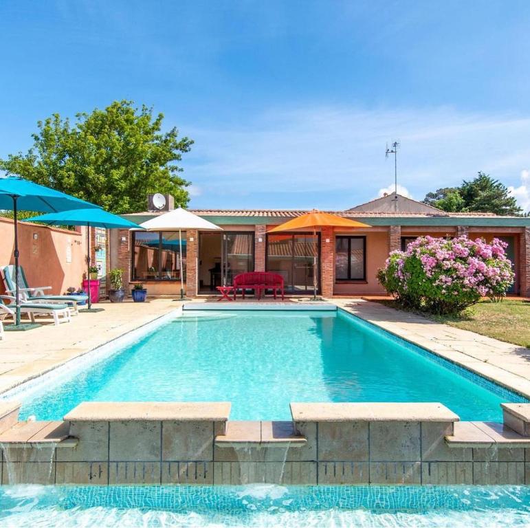 una piscina con bancos y una casa en Villa Des Plages- Piscine et spa privatifs-14pers, en Olonne-sur-Mer