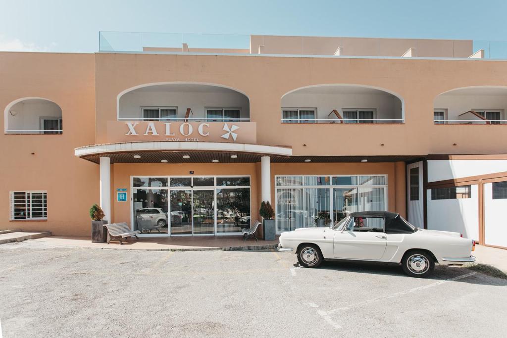 una macchina bianca parcheggiata di fronte a un edificio di Hotel Xaloc Playa a Punta Prima