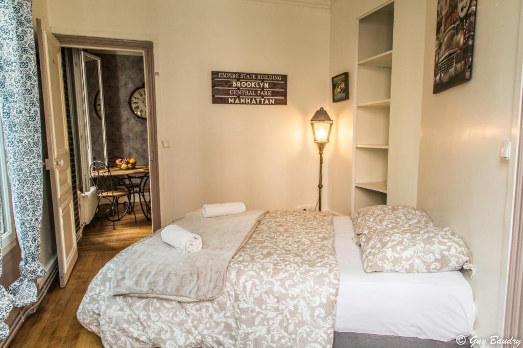 ein kleines Schlafzimmer mit einem Bett und einem Tisch in der Unterkunft Chic apart avec parking tout près de Paris in Saint-Denis