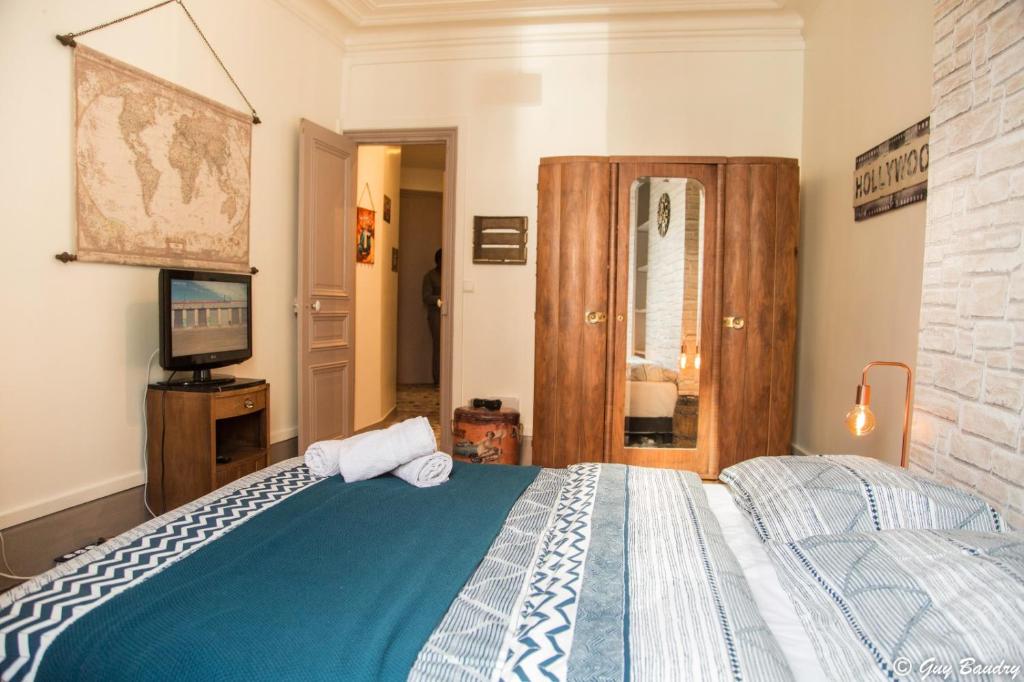 ein Schlafzimmer mit einem Bett und einem TV in der Unterkunft Chic apart avec parking tout près de Paris in Saint-Denis
