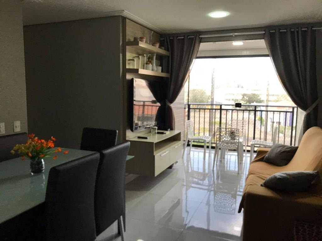 ein Wohnzimmer mit einem Tisch und einem Balkon in der Unterkunft Quarto no Dubai Residence in São Luís