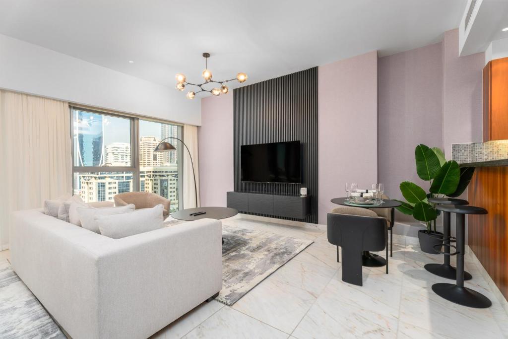 a living room with a white couch and a tv at Nasma Luxury Stays - Modern Studio Apartment with City View In DIFC in Dubai
