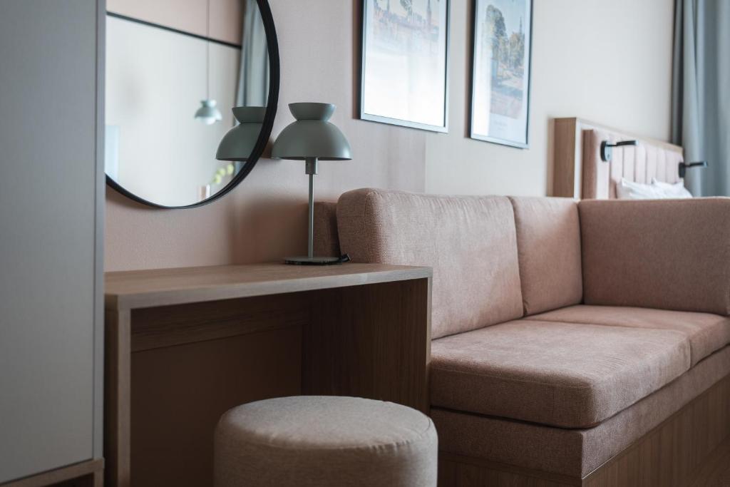 a living room with a couch and a mirror at Sky Hotel Apartments, Stockholm in Stockholm