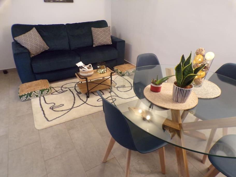uma sala de estar com uma mesa de vidro e um sofá em Logement proche centre et plage em Le Portel