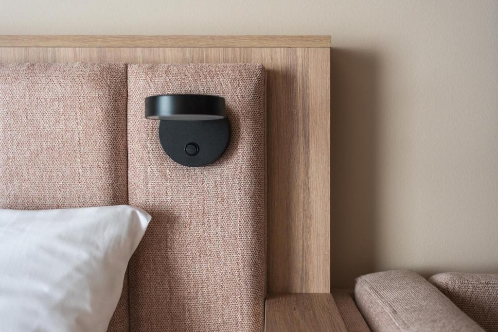 a black alarm clock on the headboard of a bed at Sky Hotel Apartments, Stockholm in Stockholm