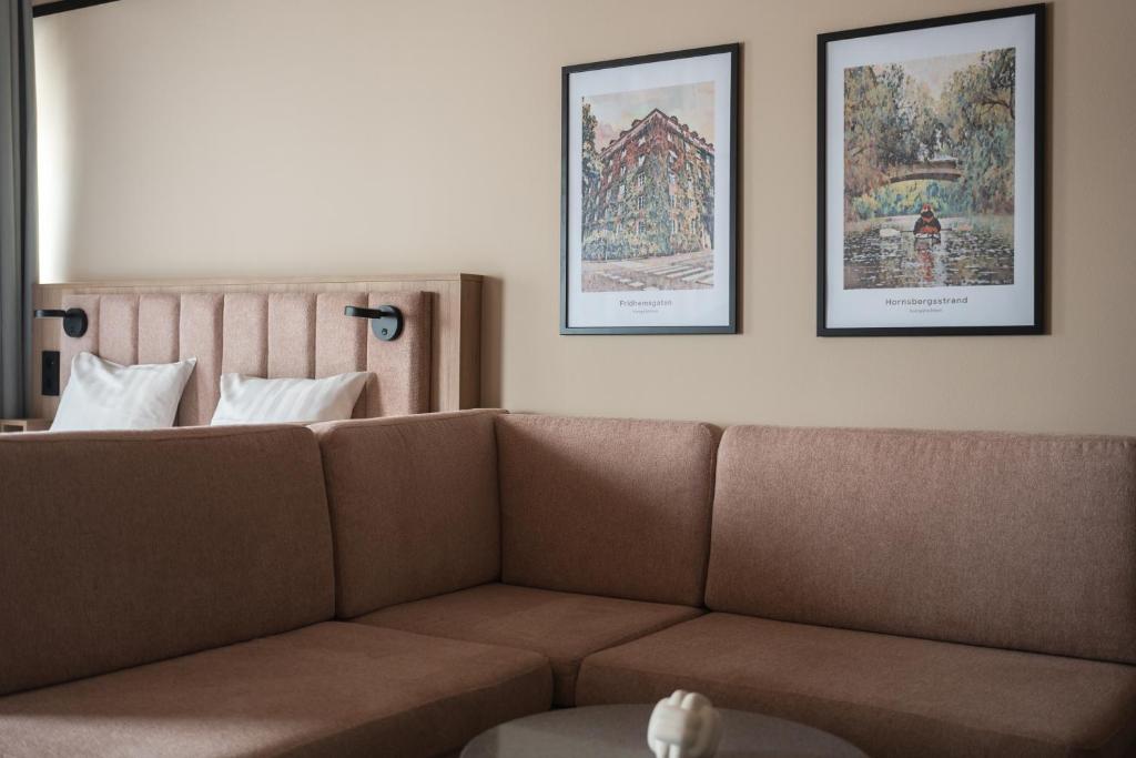 a living room with a couch and two pictures on the wall at Sky Hotel Apartments, Stockholm in Stockholm