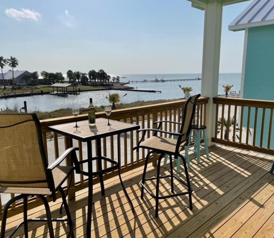 a table and chairs on a deck with a view of the ocean at Oasis On The Bay in Rockport