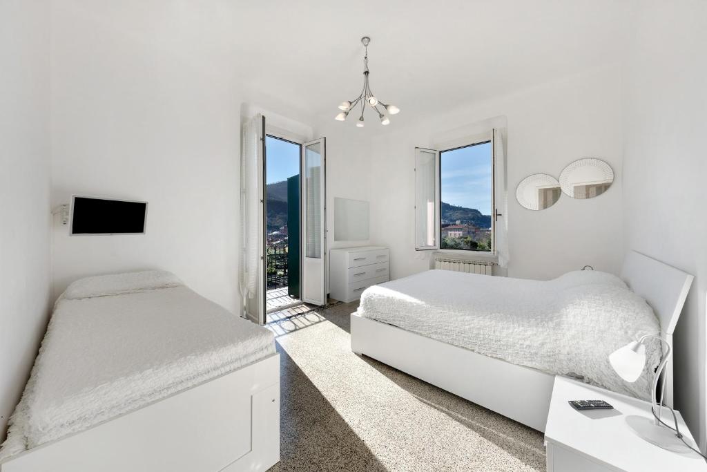 ein weißes Schlafzimmer mit 2 Betten und einem Fenster in der Unterkunft Casa Francesca in Levanto