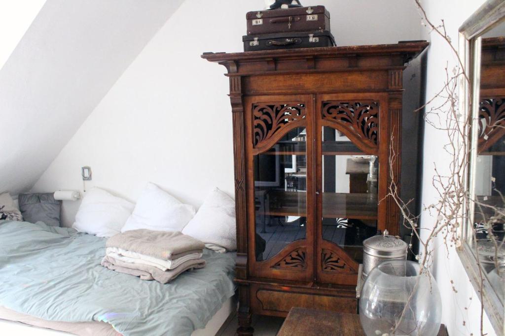 a bedroom with a wooden cabinet next to a bed at Ruhiges, helles Altbauzimmer im Stadtzentrum in Schwelm