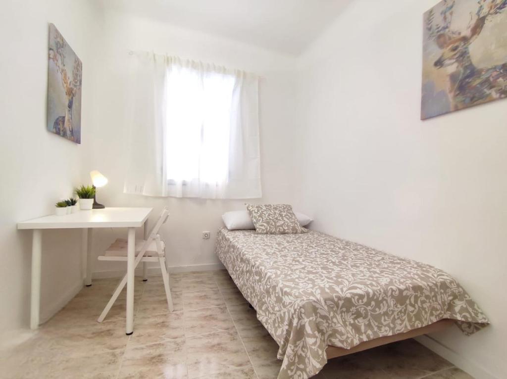 Habitación pequeña con cama y escritorio. en Cardeñosa habitaciones, en Madrid