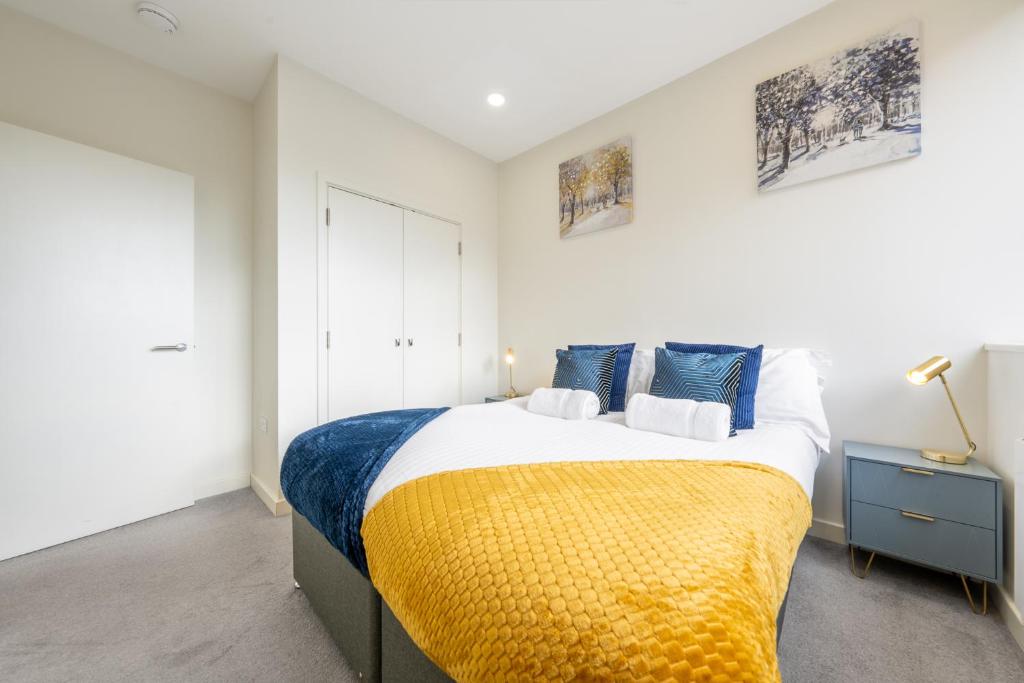 a bedroom with a large bed with a yellow blanket at Luxury 1 Bedroom serviced apartment with Roof terrace & Gym in Stevenage