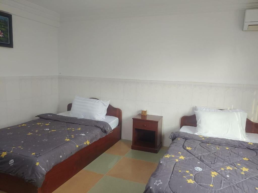 een kamer met 2 bedden en een nachtkastje bij CENTRO GUEST HOUSE in Siem Reap
