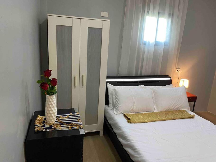 a bedroom with a bed with a vase of flowers on a table at Balai ni Gemma – cozy studio near airport in General Santos