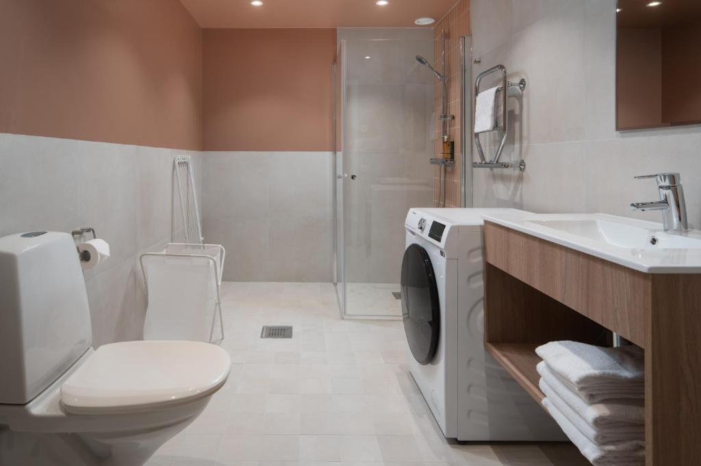 a bathroom with a toilet and a sink and a washing machine at Sky Hotel Apartments, Stockholm in Stockholm