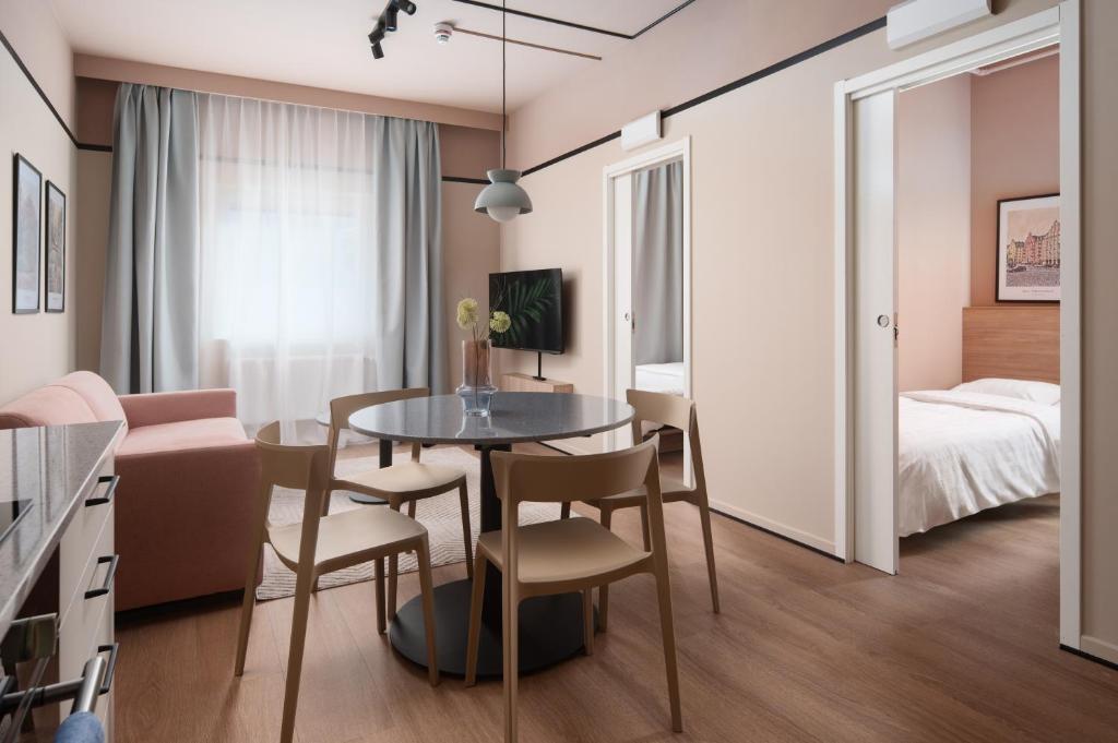 a living room with a dining room table and a bedroom at Sky Hotel Apartments, Stockholm in Stockholm