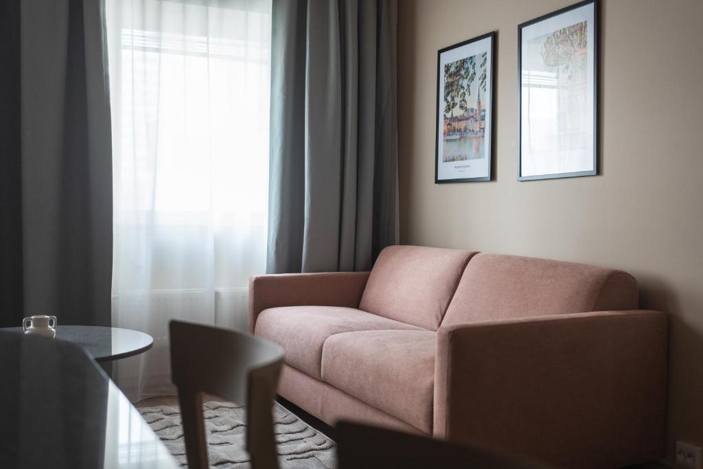 a living room with a pink couch and a table at Sky Hotel Apartments, Stockholm in Stockholm
