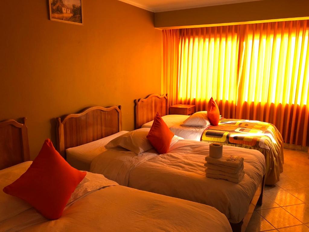 a hotel room with two beds and a window at Prince Hospedaje in Ayacucho