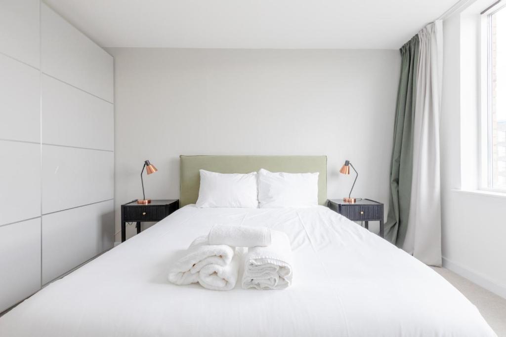 a bedroom with a white bed with towels on it at Chic Cosy & Well-Connected 1BD Flat Bermondsey! in London