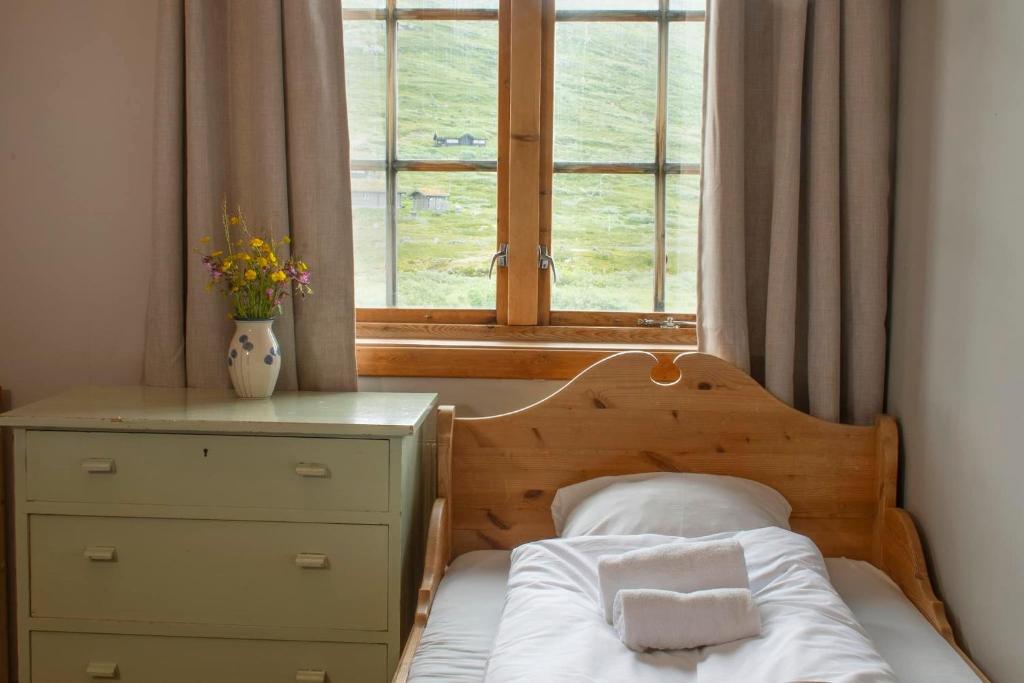 a bedroom with a bed with a dresser and a window at Tyinholmen Høyfjellsstuer in Eidsbugarden
