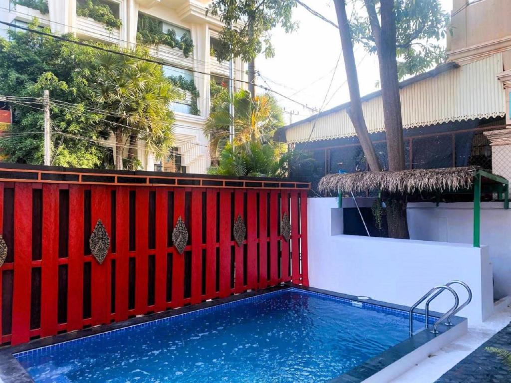 a swimming pool in front of a red fence at Centro Guest House in Siem Reap