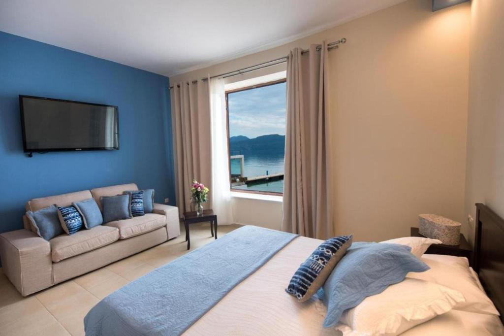 a bedroom with a bed and a couch and a window at NV Suites Nikiana Lefkada AV Properties in Nikiana