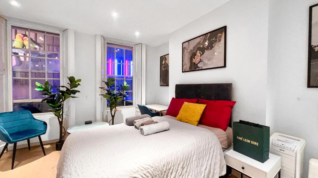 a bedroom with a white bed with red and yellow pillows at Mayfair Stylish central London Modern Suite in London