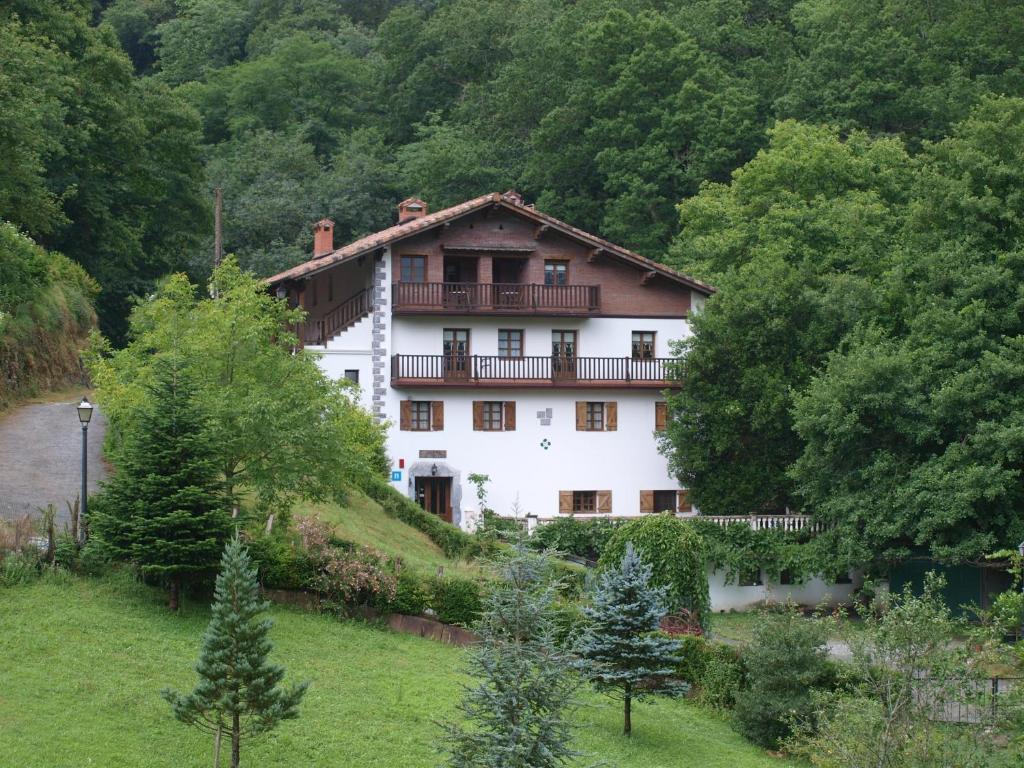 a large white house on a hill with trees at Hostal Rural Onbordi in Lesaka