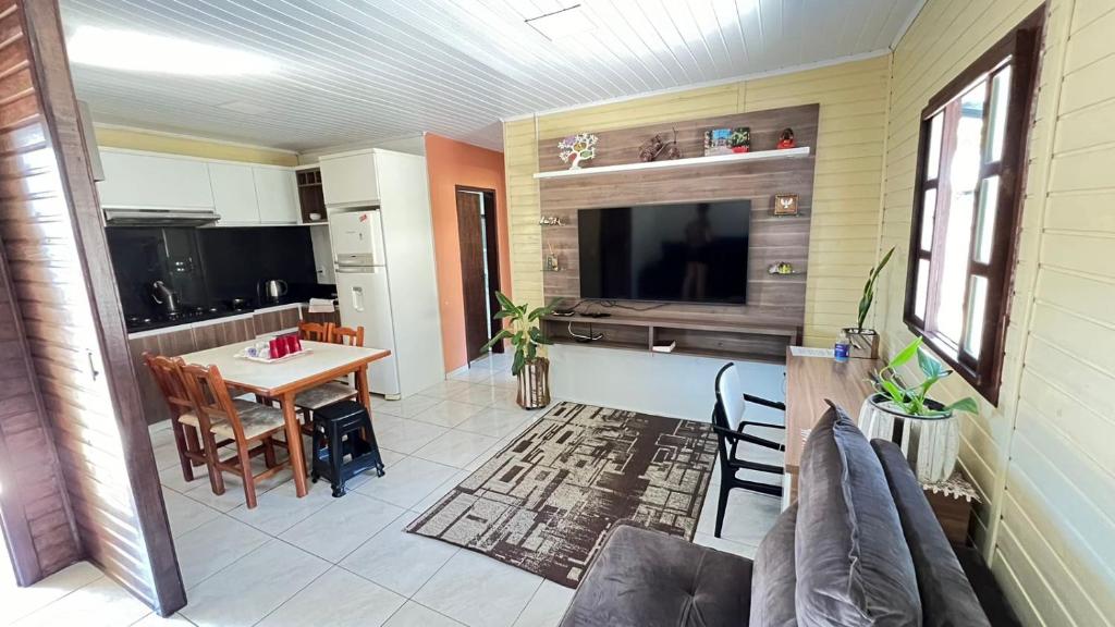 uma cozinha e sala de jantar com uma mesa e uma televisão em La Casa de Gramado em Gramado