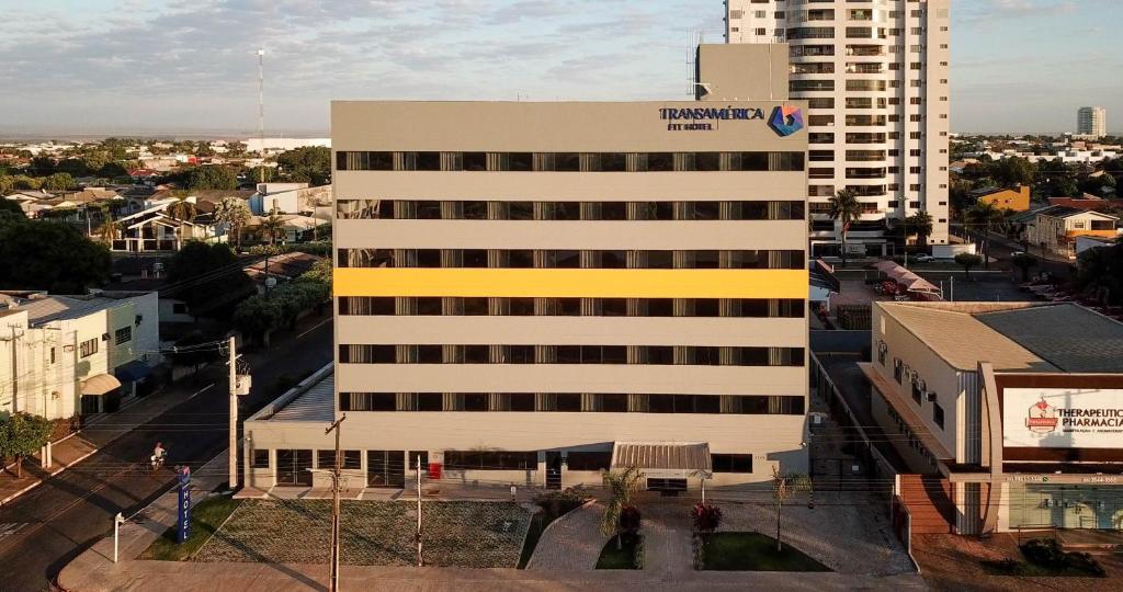 um edifício branco alto com um sinal amarelo em Transamerica Fit Sorriso em Sorriso