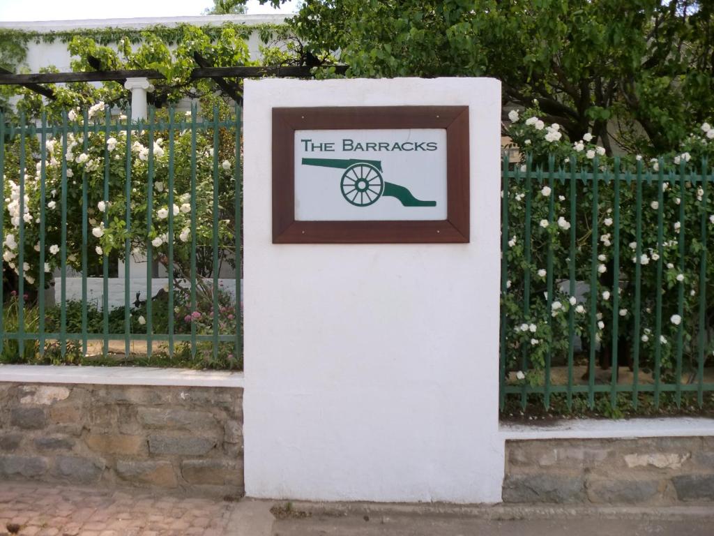 a sign on a white pole next to a fence at The Barracks in Colesberg