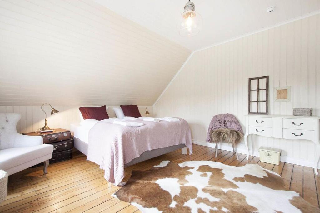 a white bedroom with a bed and a rug at SKYR Guest House in Hveragerði