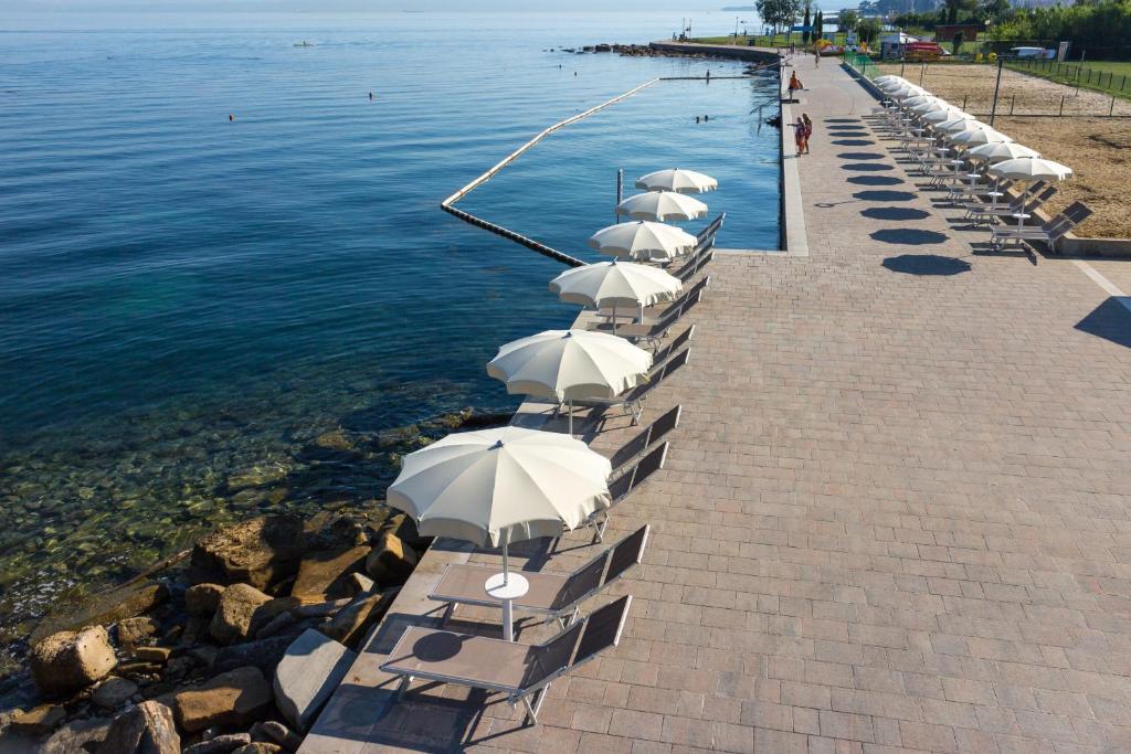 a row of chairs with umbrellas next to the water at Lazar TERRACE Apartment in Izola