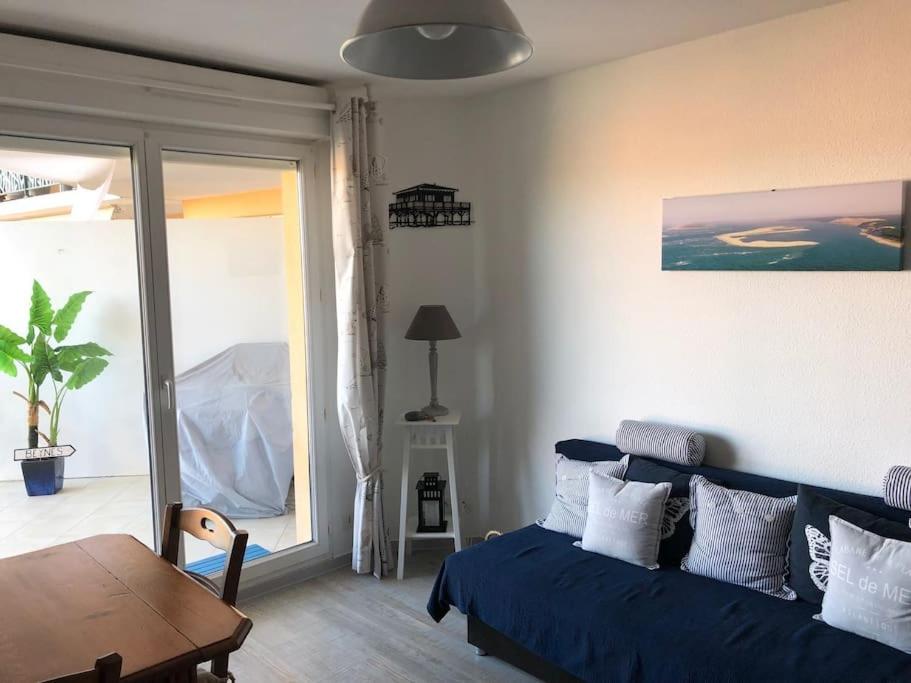 - un salon avec un lit bleu et une table dans l'établissement Appartement plein centre de La Teste-de-Buch, à La Teste-de-Buch