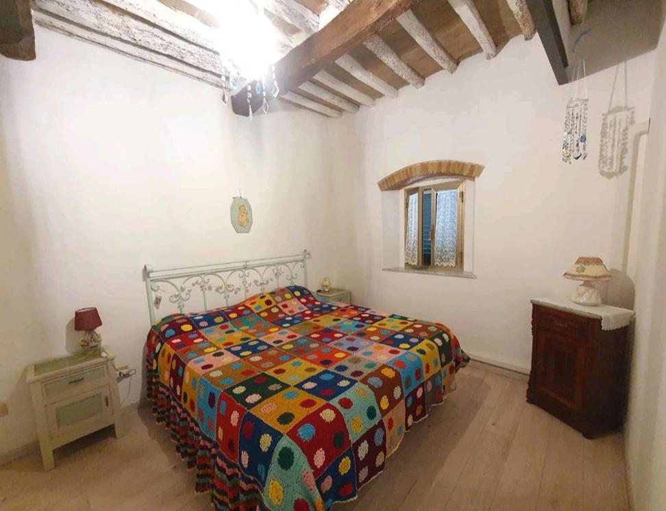 a bedroom with a bed with a colorful comforter at Casina del castello in Castelnuovo della Misericordia