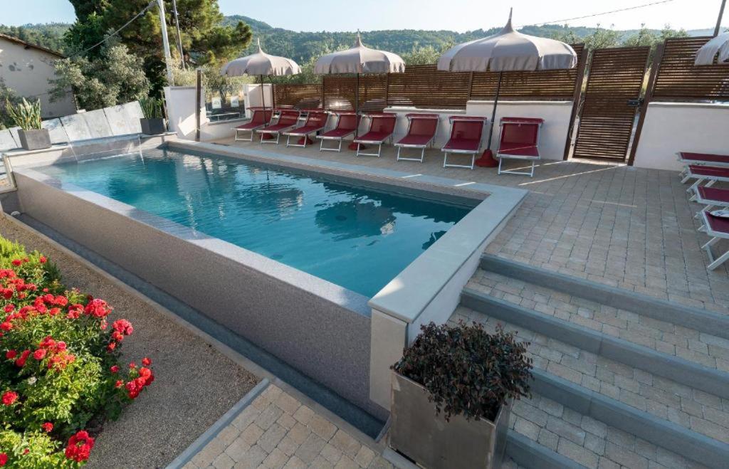 a swimming pool with chairs and tables and flowers at Dependance Villa Sassolini in Montevarchi