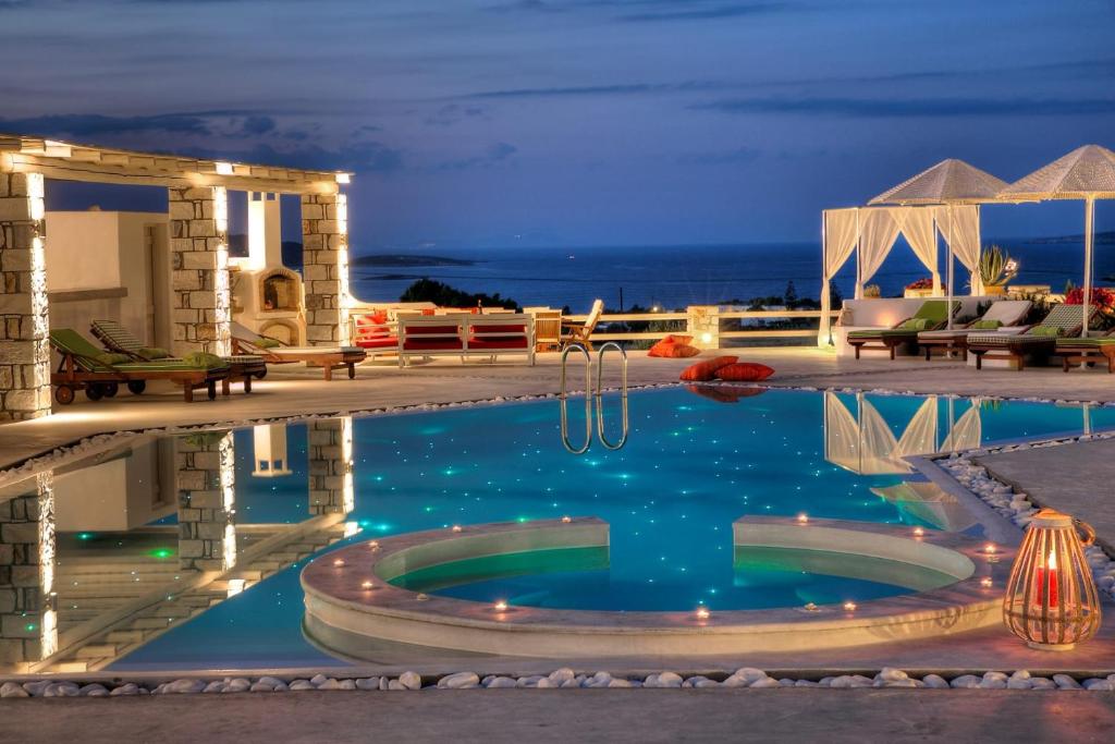 a swimming pool at night with a resort at Gorgeous Paros Villa - 3 Bedrooms - Villa Harmony - Private Outdoor Jacuzzi and Garden Views - Naousa in Livadia