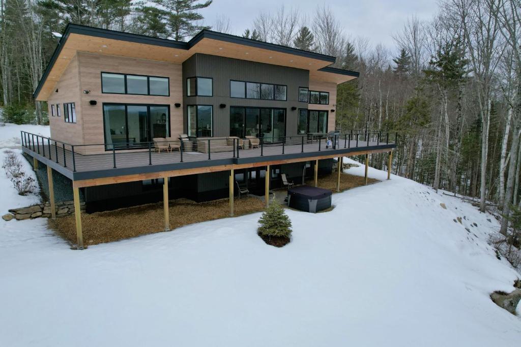 a large house with a deck in the snow at 1A Maple Lodge Stunning luxury Scandinavian style home with great views in Bethlehem