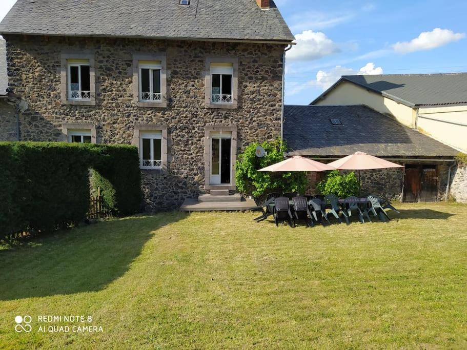 a stone house with chairs and umbrellas in the yard at Gite au sein du Parc des Volcans d&#39;Auvergne, tous commerces à pied in Neussargues-Moissac