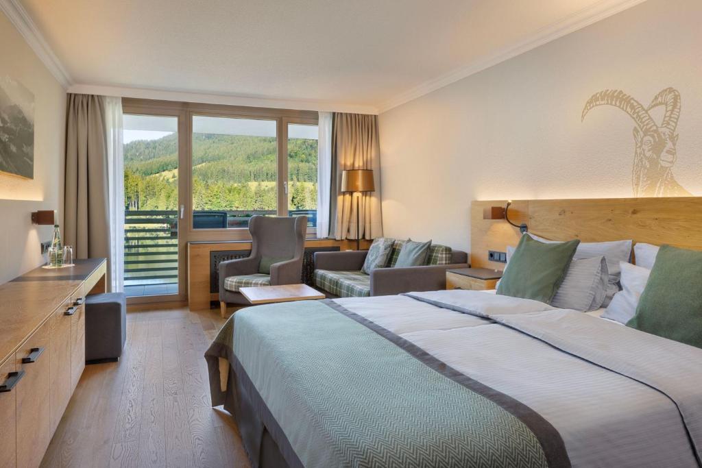 a hotel room with a bed and a living room at Arabella Alpenhotel am Spitzingsee, a Tribute Portfolio Hotel in Spitzingsee