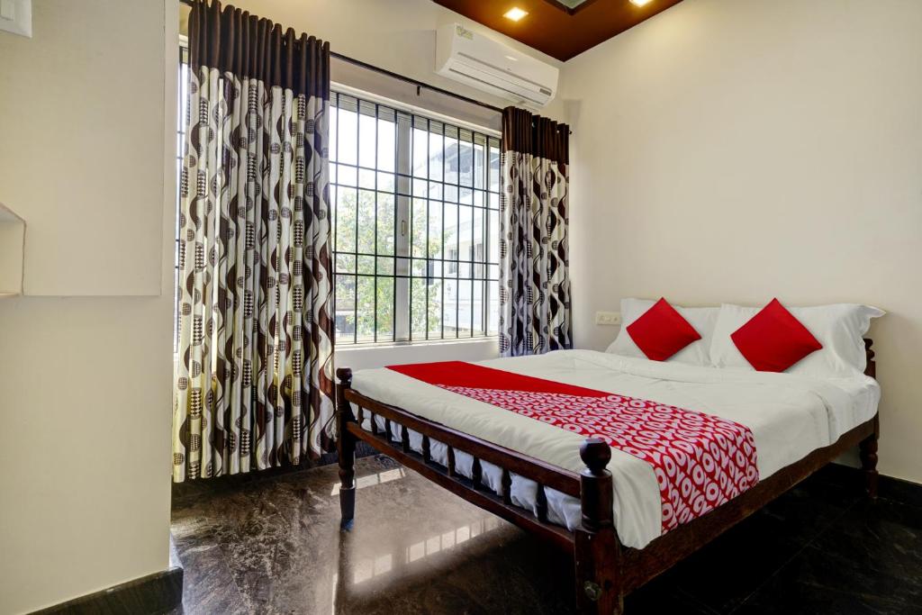 a bedroom with a bed with red pillows and a window at OYO Hi 5 Apartments in Cochin