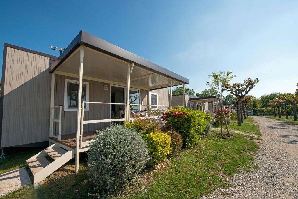 een klein huis met een veranda en een aantal struiken bij Camping Belvedere in Lazise