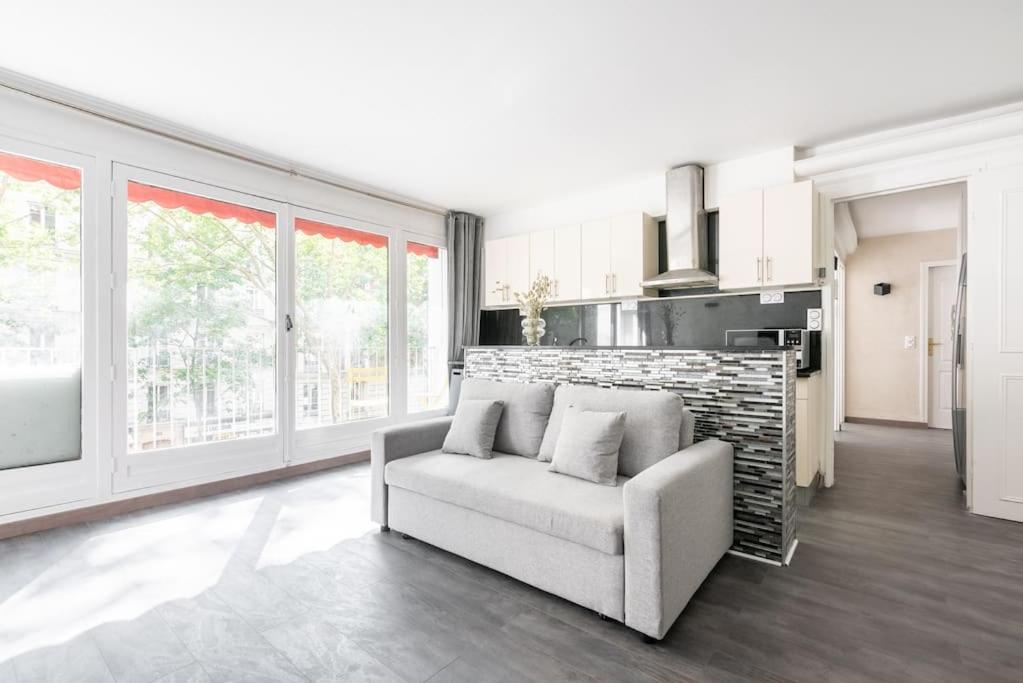 un salon avec un canapé et quelques fenêtres dans l'établissement Appartement ensoleillé Buttes Chaumont - III, à Paris