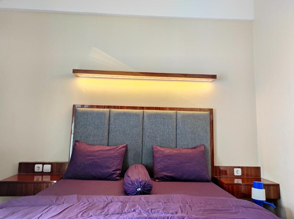 ein Schlafzimmer mit einem lila Bett mit lila Kissen in der Unterkunft Transpark Juanda by Bonzela Property in Padurenan