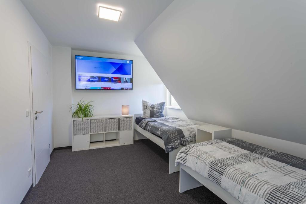 ニュルンベルクにあるClaudias Apartment - 20 Minuten bis Messe Nürnbergのベッド2台、壁掛けテレビが備わる客室です。