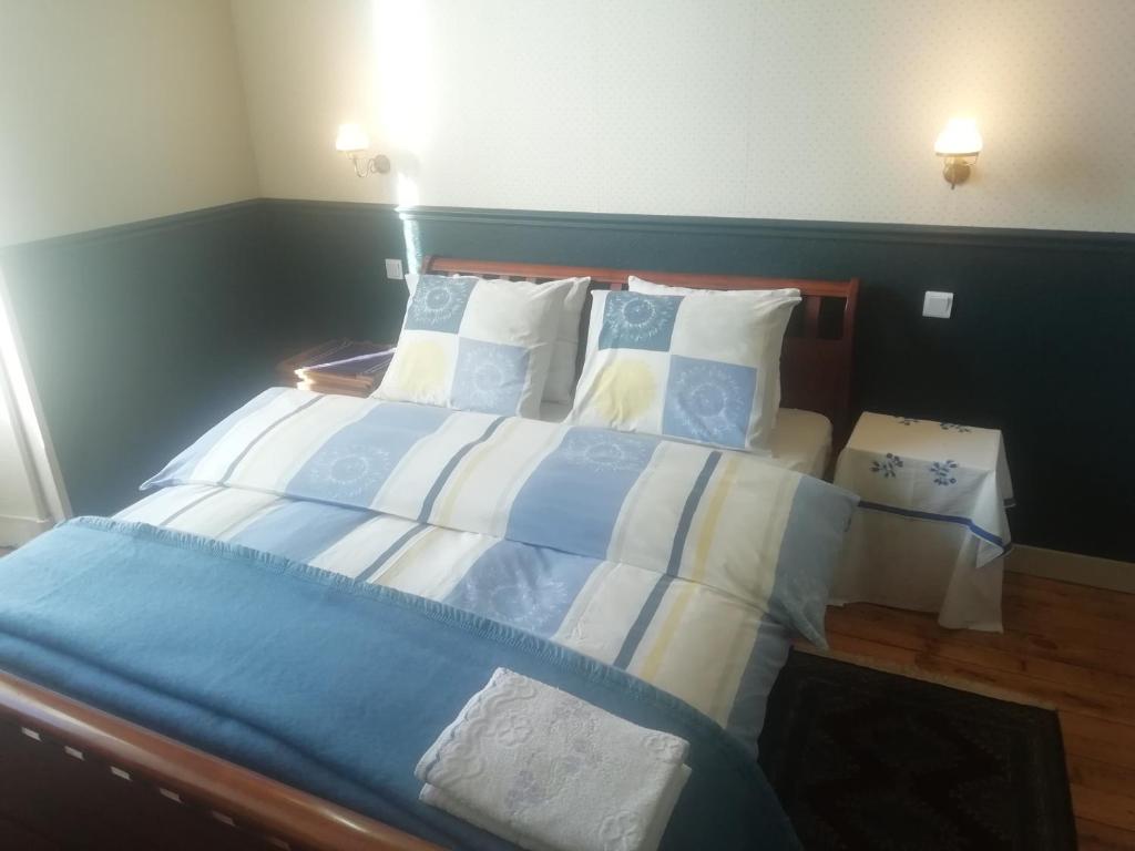 Cama grande con sábanas y almohadas azules y blancas en Thunder Roadhouse, en La Mothe-Saint-Héray