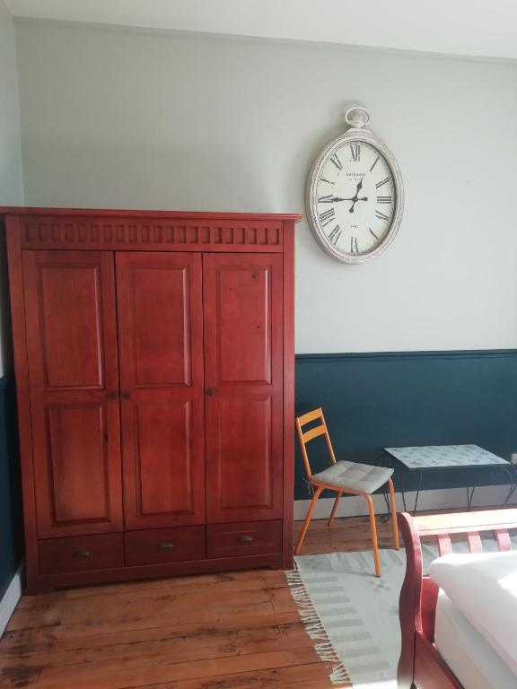 a bedroom with a red cabinet and a clock on the wall at Thunder Roadhouse in La Mothe-Saint-Héray