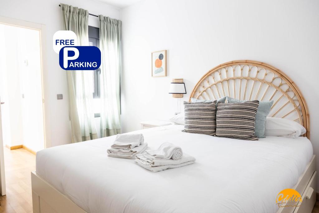 Un dormitorio con una cama blanca con toallas. en Rincon del Mar - FREE PARKING by Cadiz Time, en Cádiz