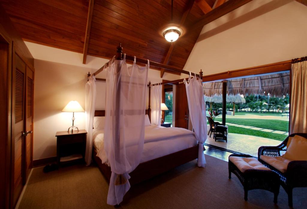 a bedroom with a canopy bed and a patio at Victoria House Resort & Spa in San Pedro