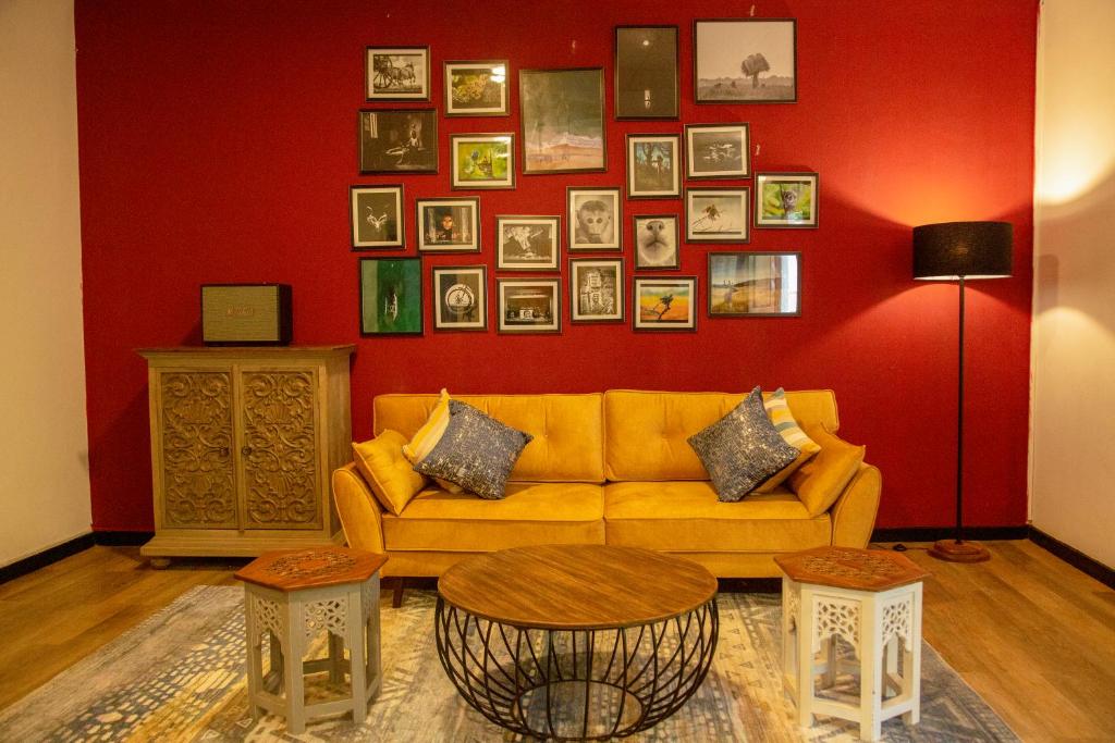 a living room with a yellow couch and a red wall at TIKI TAKA in Kandy